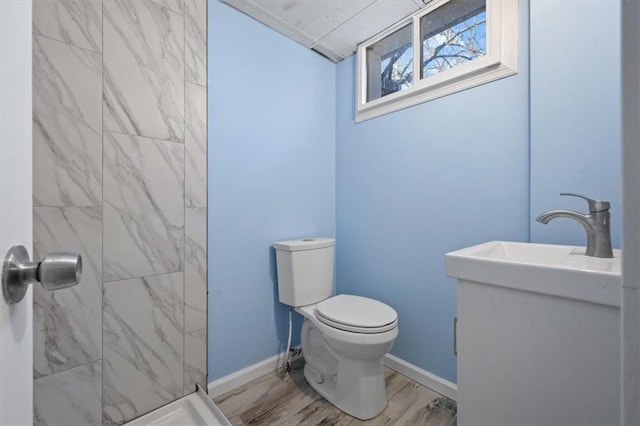 bathroom with hardwood / wood-style floors, toilet, sink, and a tile shower