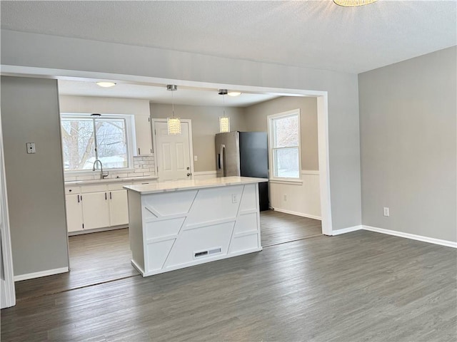 kitchen featuring dark wood-type flooring, white cabinetry, hanging light fixtures, a kitchen island, and decorative backsplash