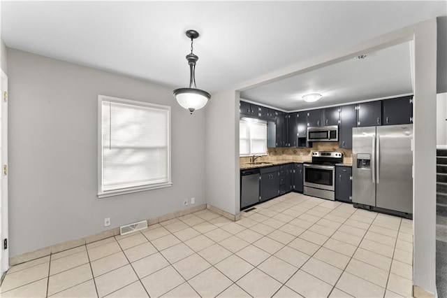 kitchen with tasteful backsplash, plenty of natural light, hanging light fixtures, and appliances with stainless steel finishes