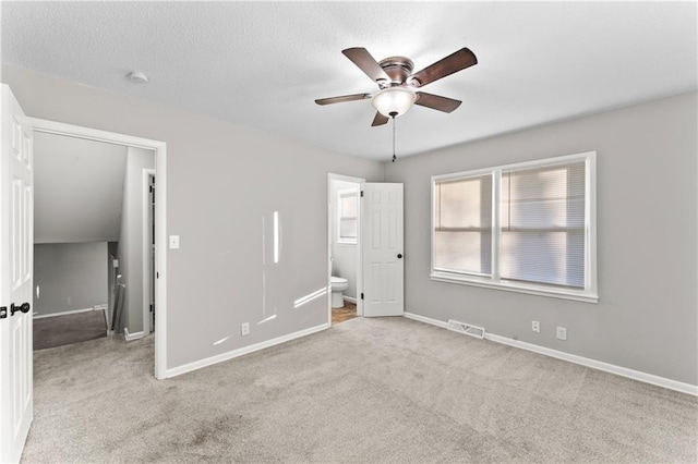 unfurnished bedroom with ceiling fan, light carpet, and connected bathroom