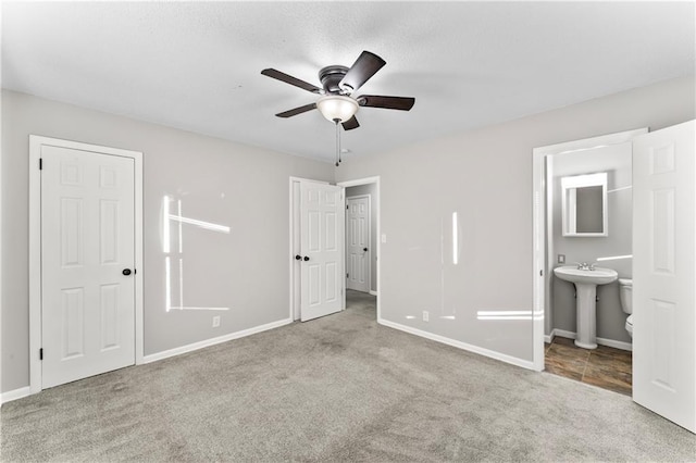 unfurnished bedroom featuring light colored carpet, ensuite bath, ceiling fan, and sink