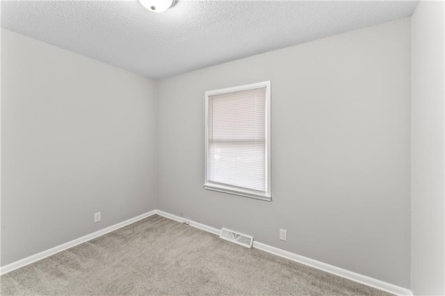 carpeted spare room with a textured ceiling