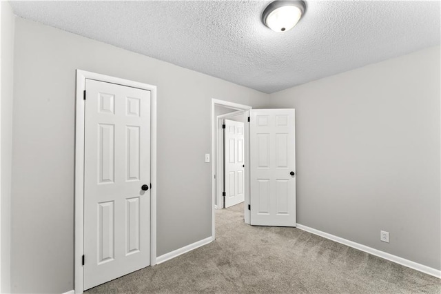 unfurnished bedroom featuring light colored carpet, a textured ceiling, and a closet