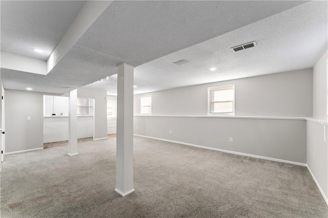 basement with a textured ceiling and light carpet