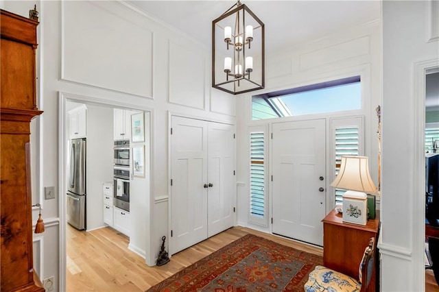 foyer entrance with light hardwood / wood-style floors and an inviting chandelier