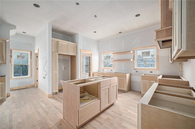 kitchen with a kitchen island, a textured ceiling, light brown cabinetry, and light hardwood / wood-style flooring