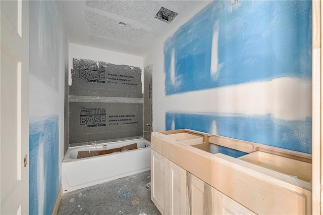 bathroom with a washtub and a textured ceiling