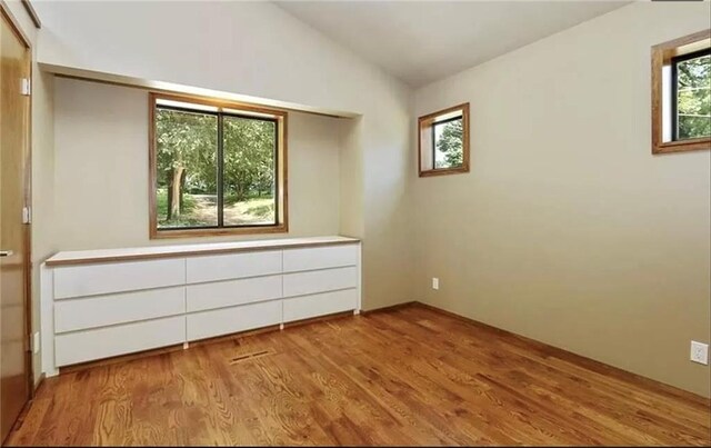 unfurnished bedroom with light hardwood / wood-style floors and vaulted ceiling