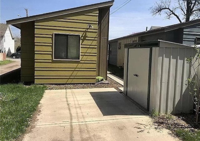 view of side of home featuring a patio area and a shed