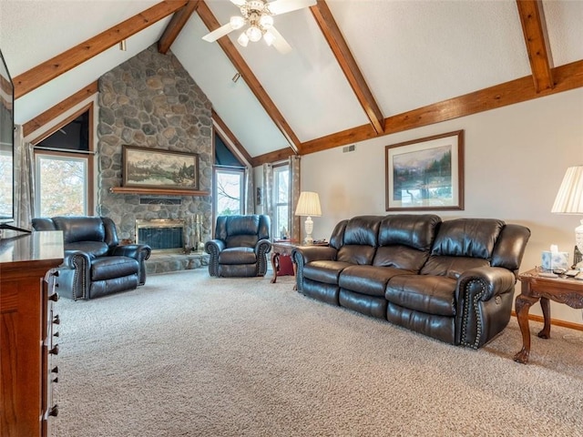 carpeted living room featuring ceiling fan, a stone fireplace, high vaulted ceiling, and beam ceiling