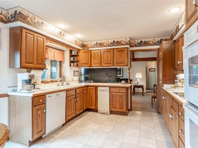 kitchen with kitchen peninsula, a textured ceiling, white appliances, and sink