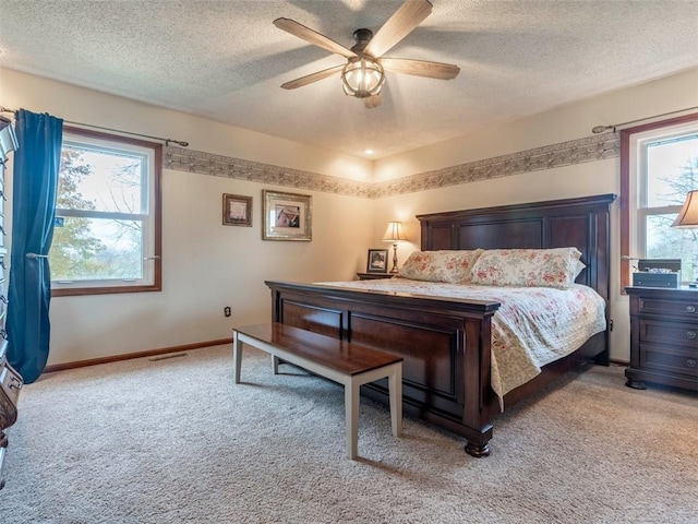 carpeted bedroom with multiple windows, ceiling fan, and a textured ceiling