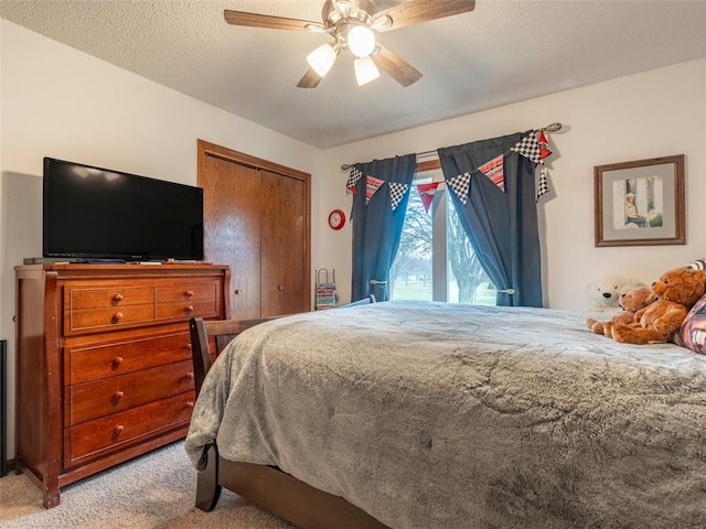 carpeted bedroom with a textured ceiling, a closet, and ceiling fan