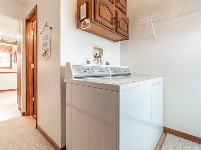 clothes washing area featuring cabinets, light carpet, and washer and clothes dryer