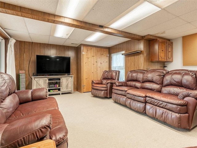 carpeted living room with a drop ceiling and wood walls