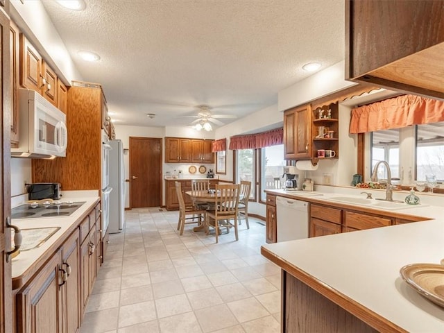 kitchen with ceiling fan, white appliances, sink, and a textured ceiling