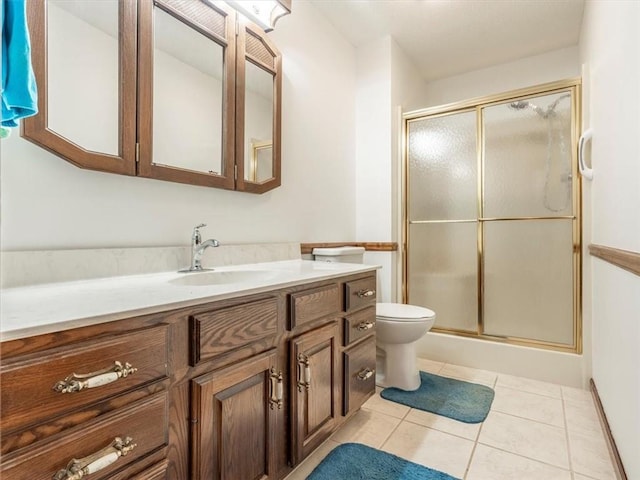 bathroom with tile patterned floors, toilet, a shower with shower door, and vanity