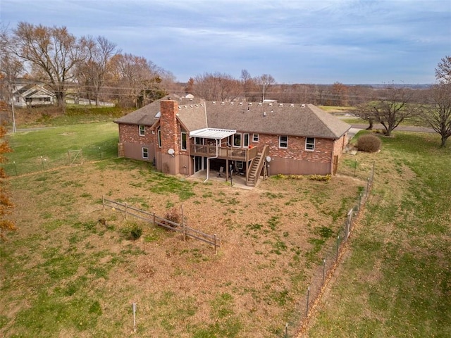 rear view of property featuring a wooden deck and a lawn