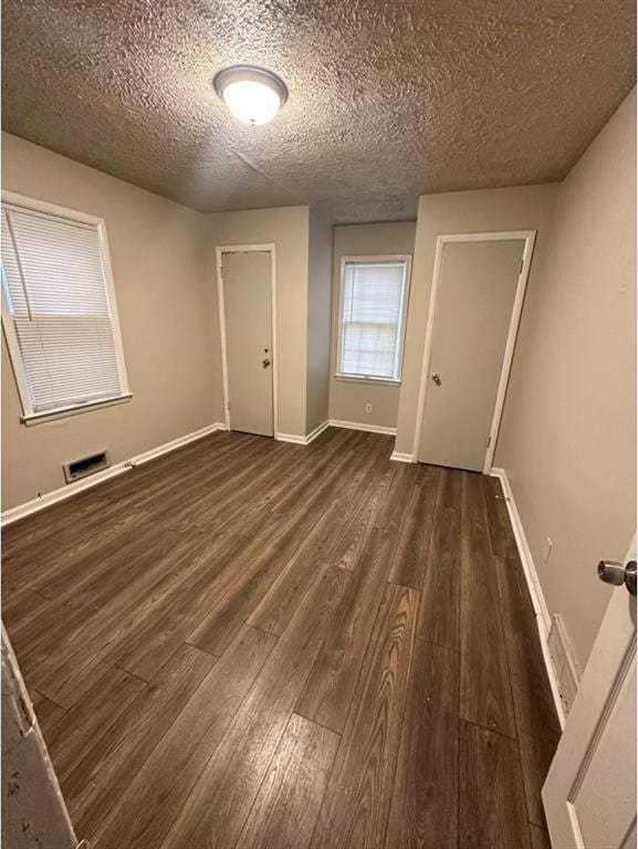 spare room with a textured ceiling and dark hardwood / wood-style floors