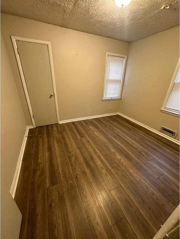 spare room featuring dark hardwood / wood-style flooring and a textured ceiling