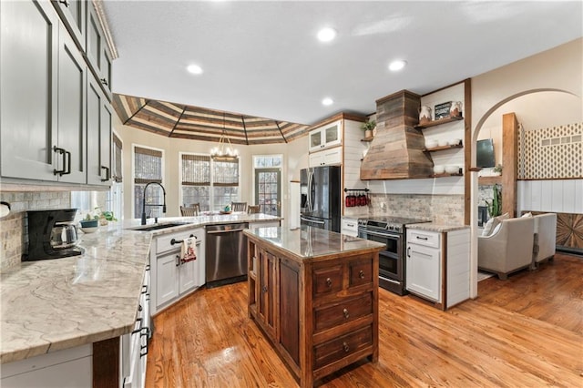 kitchen featuring light hardwood / wood-style floors, light stone countertops, kitchen peninsula, and appliances with stainless steel finishes