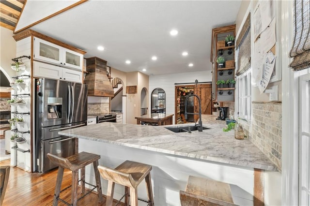 kitchen featuring a breakfast bar, sink, a barn door, appliances with stainless steel finishes, and kitchen peninsula