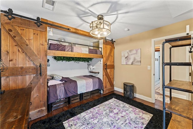 bedroom with a barn door and dark wood-type flooring