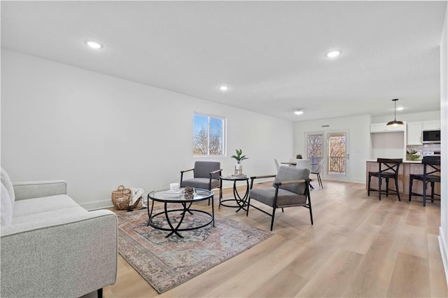 living area with recessed lighting, light wood-type flooring, and plenty of natural light