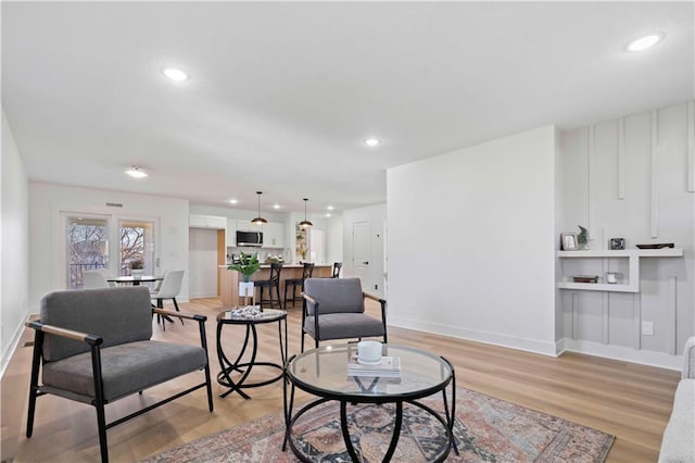 living room with recessed lighting, baseboards, and light wood-style floors