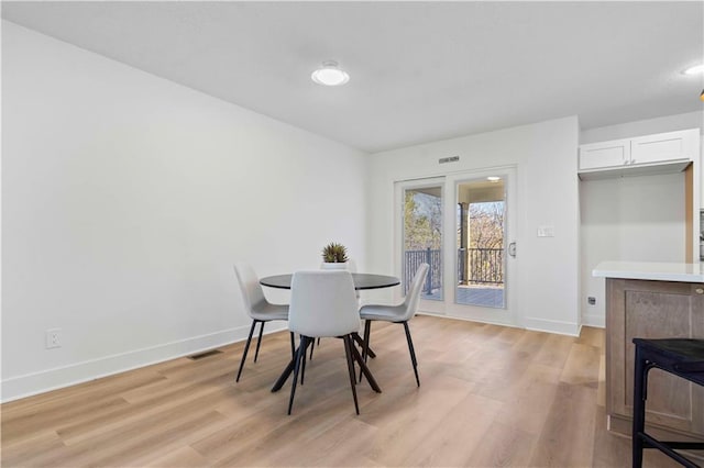 dining area with light wood-style flooring, visible vents, and baseboards