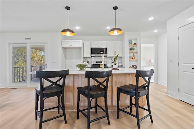 kitchen with light wood-type flooring, appliances with stainless steel finishes, white cabinets, and light countertops