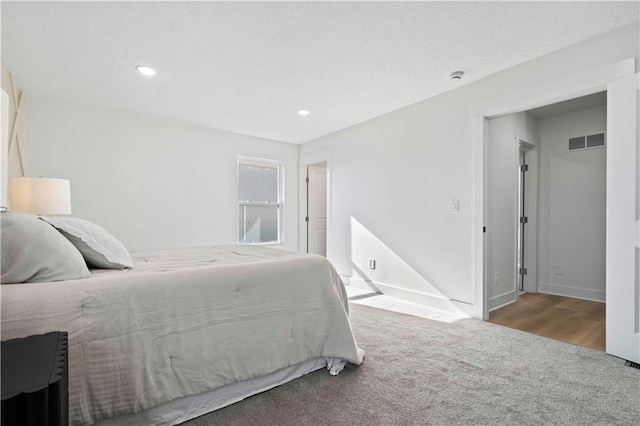 carpeted bedroom with visible vents, recessed lighting, a textured ceiling, and baseboards