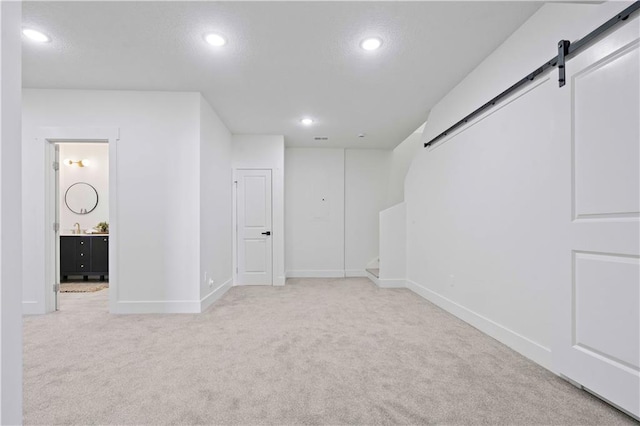 below grade area featuring a barn door, recessed lighting, carpet, and baseboards