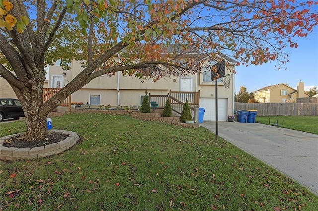 exterior space featuring a front yard, fence, an attached garage, stucco siding, and concrete driveway