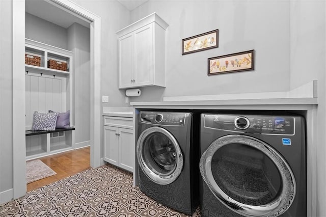 washroom featuring cabinets, independent washer and dryer, and light hardwood / wood-style flooring