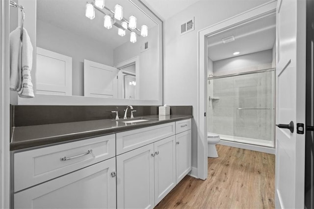 bathroom with vanity, hardwood / wood-style floors, a shower with shower door, and toilet