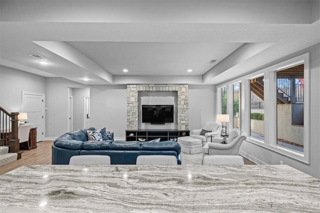 living room with a raised ceiling and light wood-type flooring