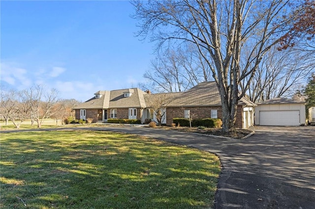 view of front facade featuring a garage, an outbuilding, and a front lawn