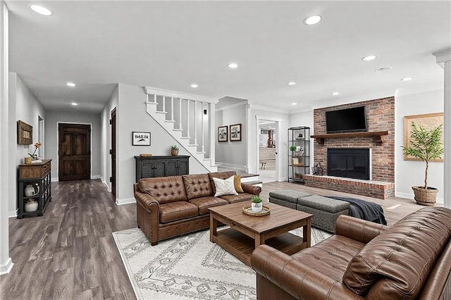 living room featuring recessed lighting, stairway, a brick fireplace, wood finished floors, and baseboards