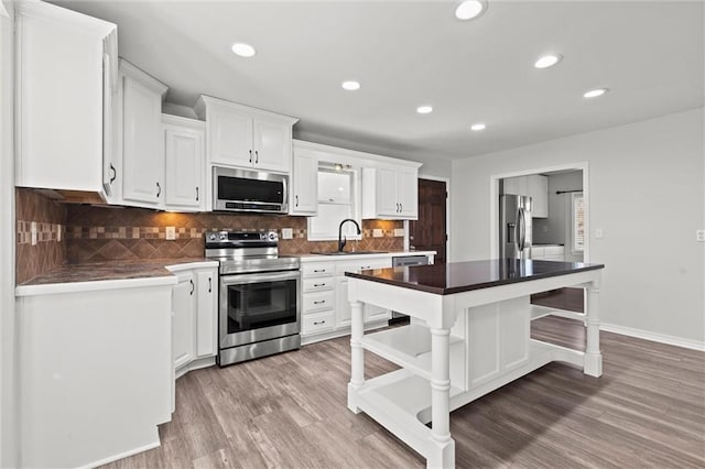 kitchen featuring appliances with stainless steel finishes, a center island, light wood-style floors, open shelves, and a sink