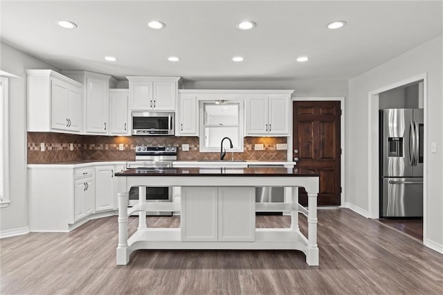 kitchen with stainless steel appliances, white cabinetry, a sink, and a kitchen island