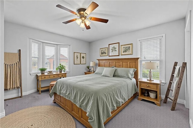 bedroom featuring light colored carpet, multiple windows, ceiling fan, and baseboards