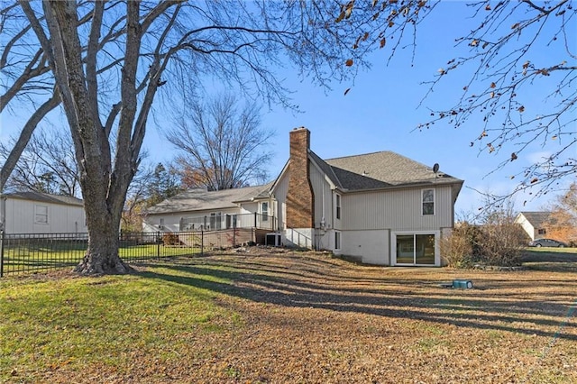 back of property with a yard, a chimney, and fence