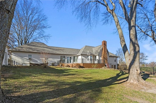 back of property featuring a yard, a chimney, fence, and a wooden deck