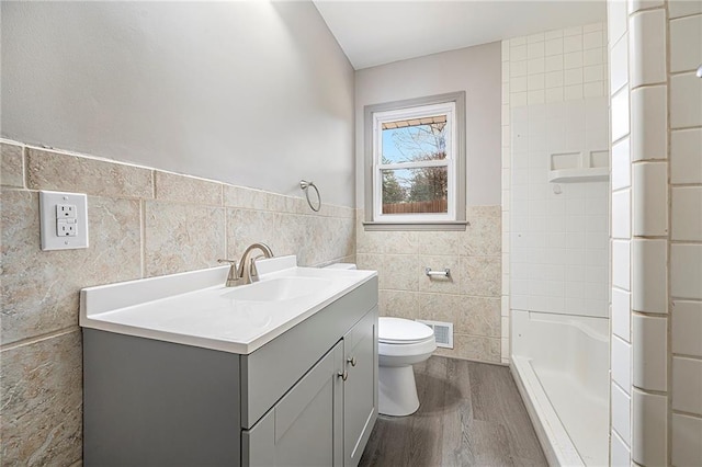 bathroom with vanity, hardwood / wood-style flooring, toilet, tile walls, and walk in shower