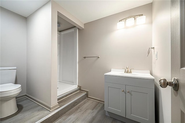 bathroom with vanity, toilet, wood-type flooring, and a shower