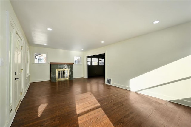 unfurnished living room with dark wood-type flooring and a tiled fireplace