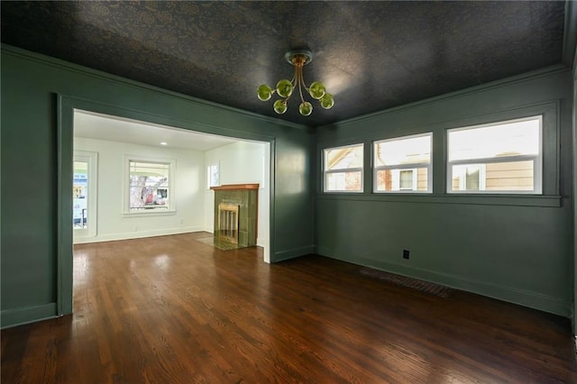 empty room featuring a fireplace, ornamental molding, and dark wood-type flooring