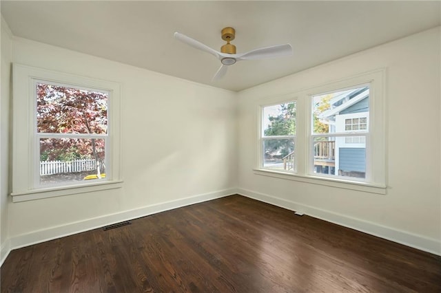 empty room with ceiling fan, dark wood-type flooring, and a wealth of natural light