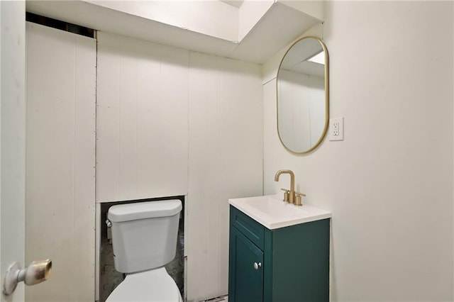 bathroom featuring wooden walls, vanity, and toilet